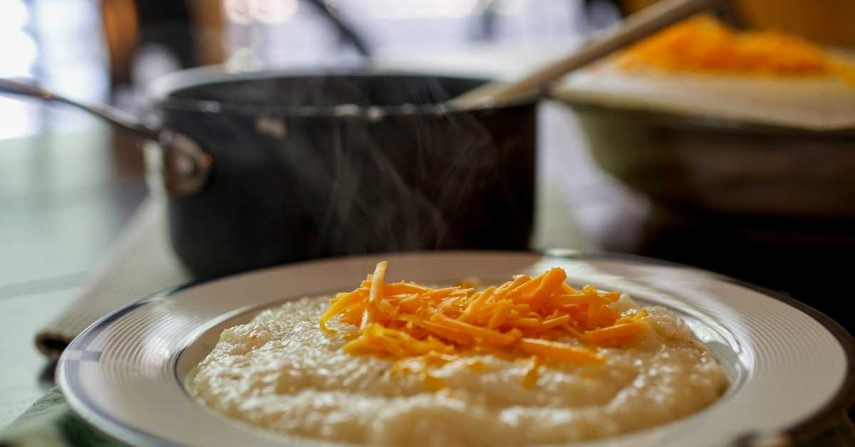 Bowl of hot grits topped with grated cheddar cheese